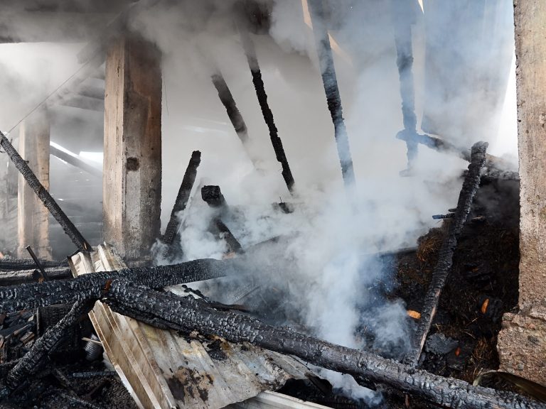 Interior of a burnt building with charred wood and smoke.