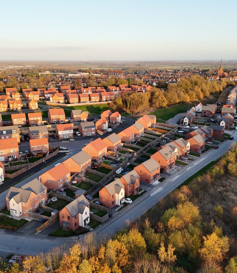 Aerial view of suburban housing with greenery and trees in autumn colours.