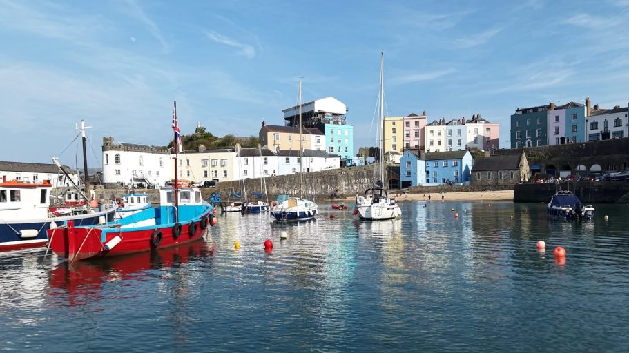 Tenby Harbour scene with boats and colourful buildings under a clear blue sky.