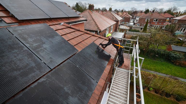 Worker installing solar panels on a residential roof.